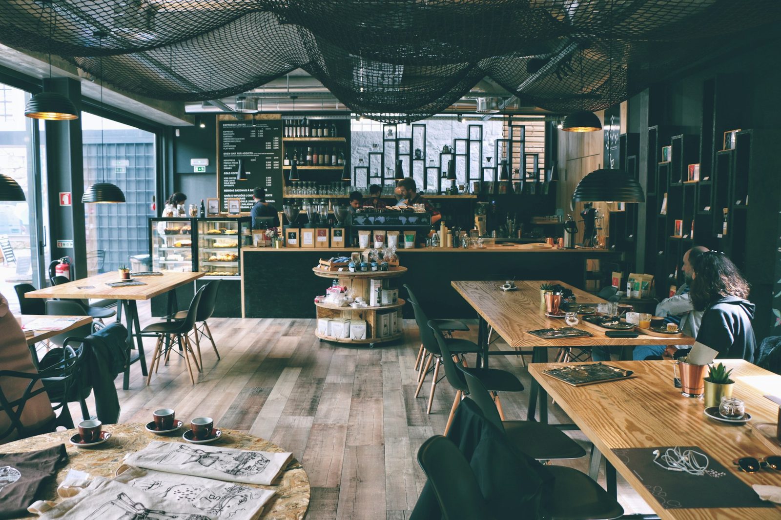 Dark green cafe interior with communal tables and pendant lighting.