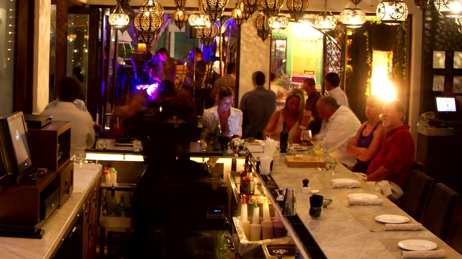 A busy restaurant bar at night, full of diners under warm pendant lights.