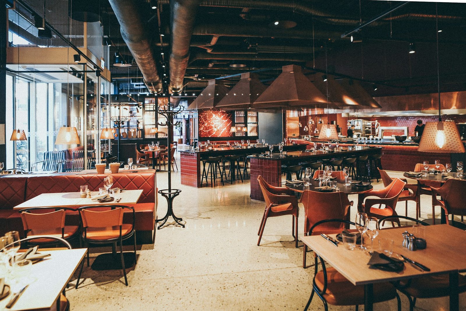 Warm restaurant dining room with an open kitchen.